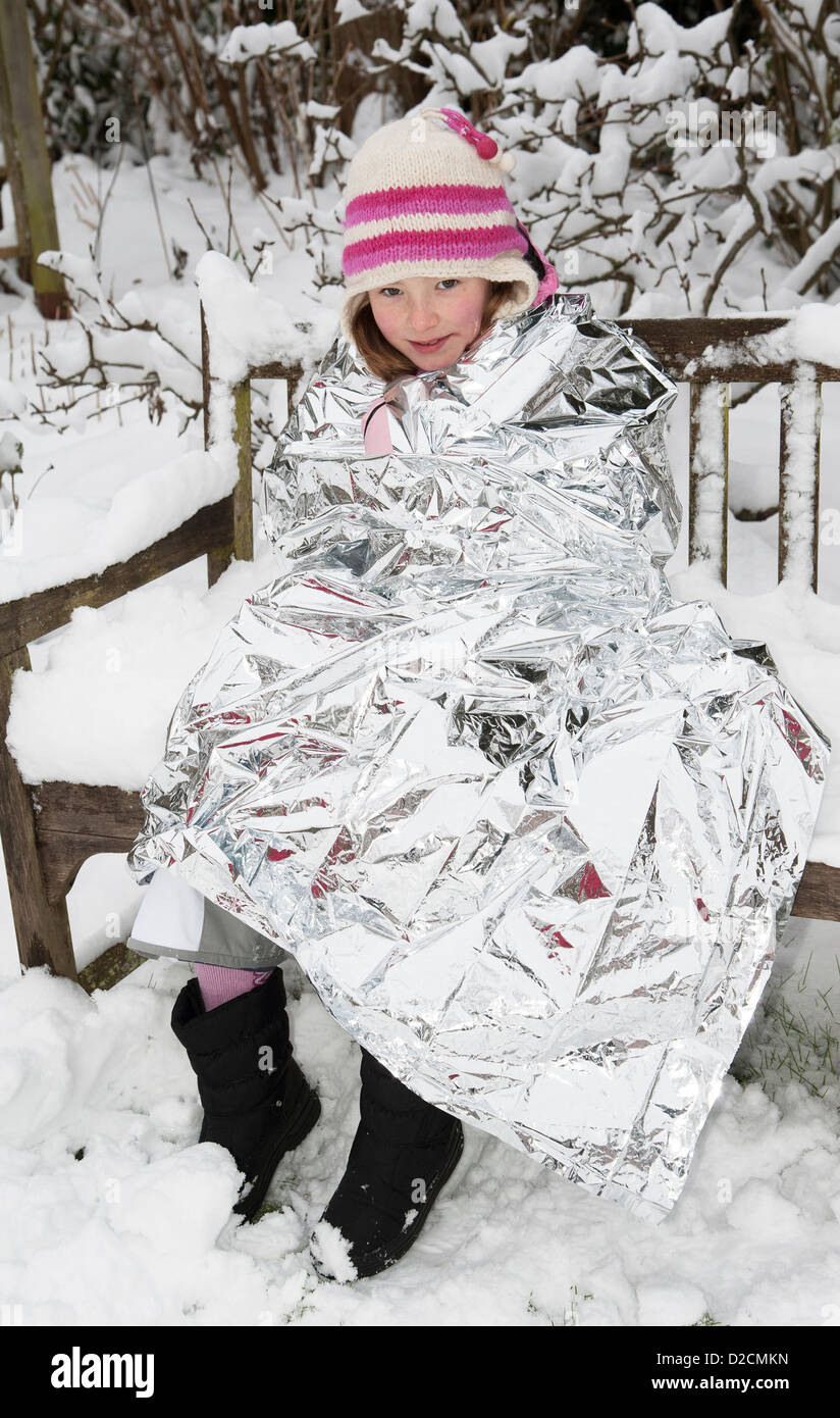 Mit Hilfe einer Folie Decke behalten die Hitze und halten den Winter kalt in einem verschneiten Garten Stockfoto