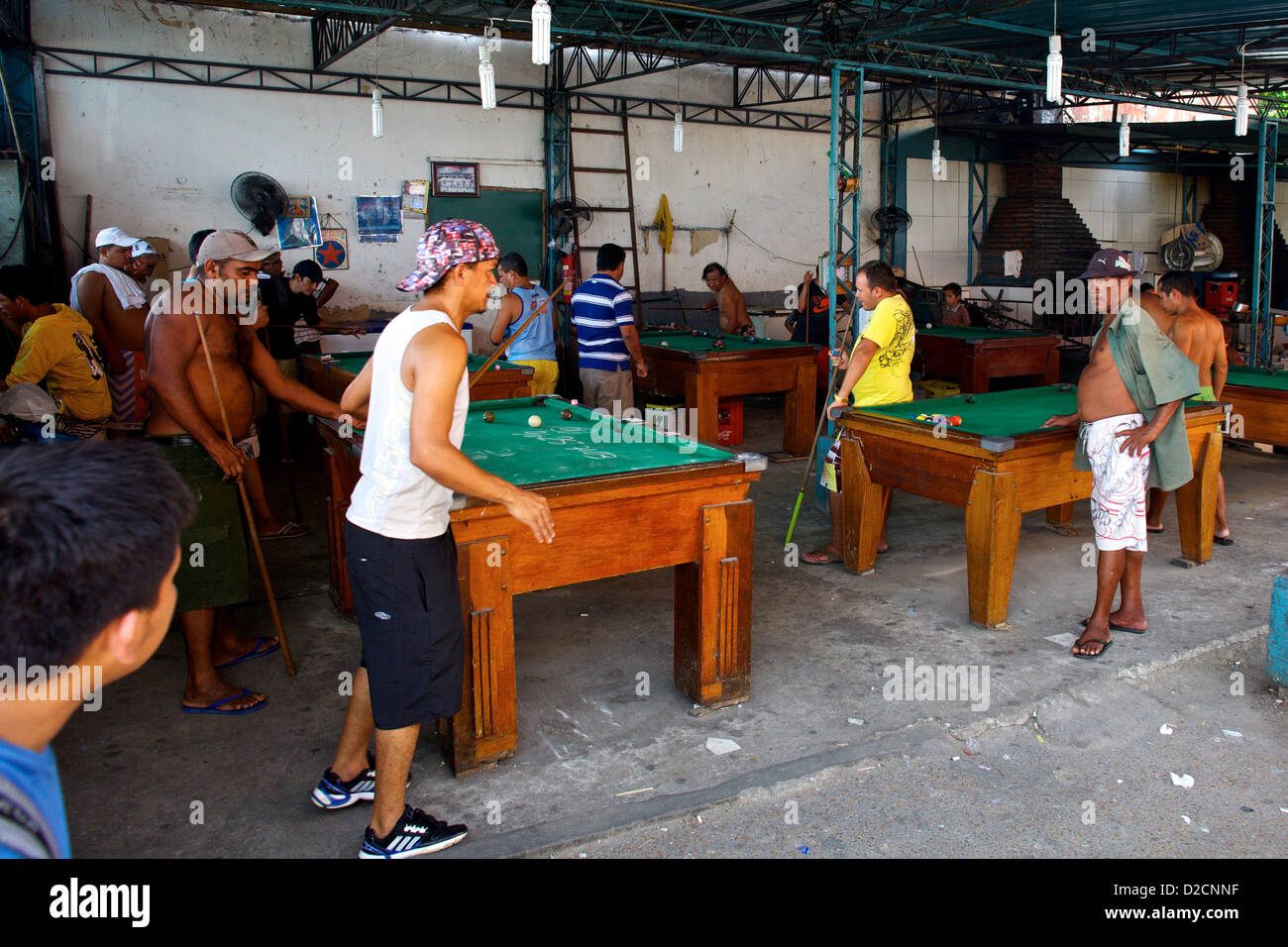 Einheimische Männer spielen eine lebhafte Partie Billard unter einem rustikalen Zinndach in Manaus, Brasilien. Stockfoto
