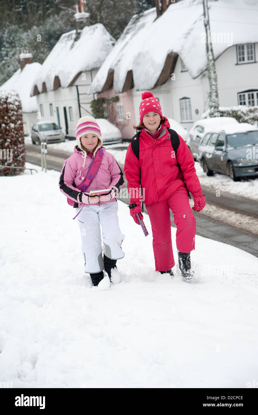 Kinder gehen zur Schule in einem ländlichen Dorf in Hampshire England UK entlang Schnee bedeckt Straße Stockfoto