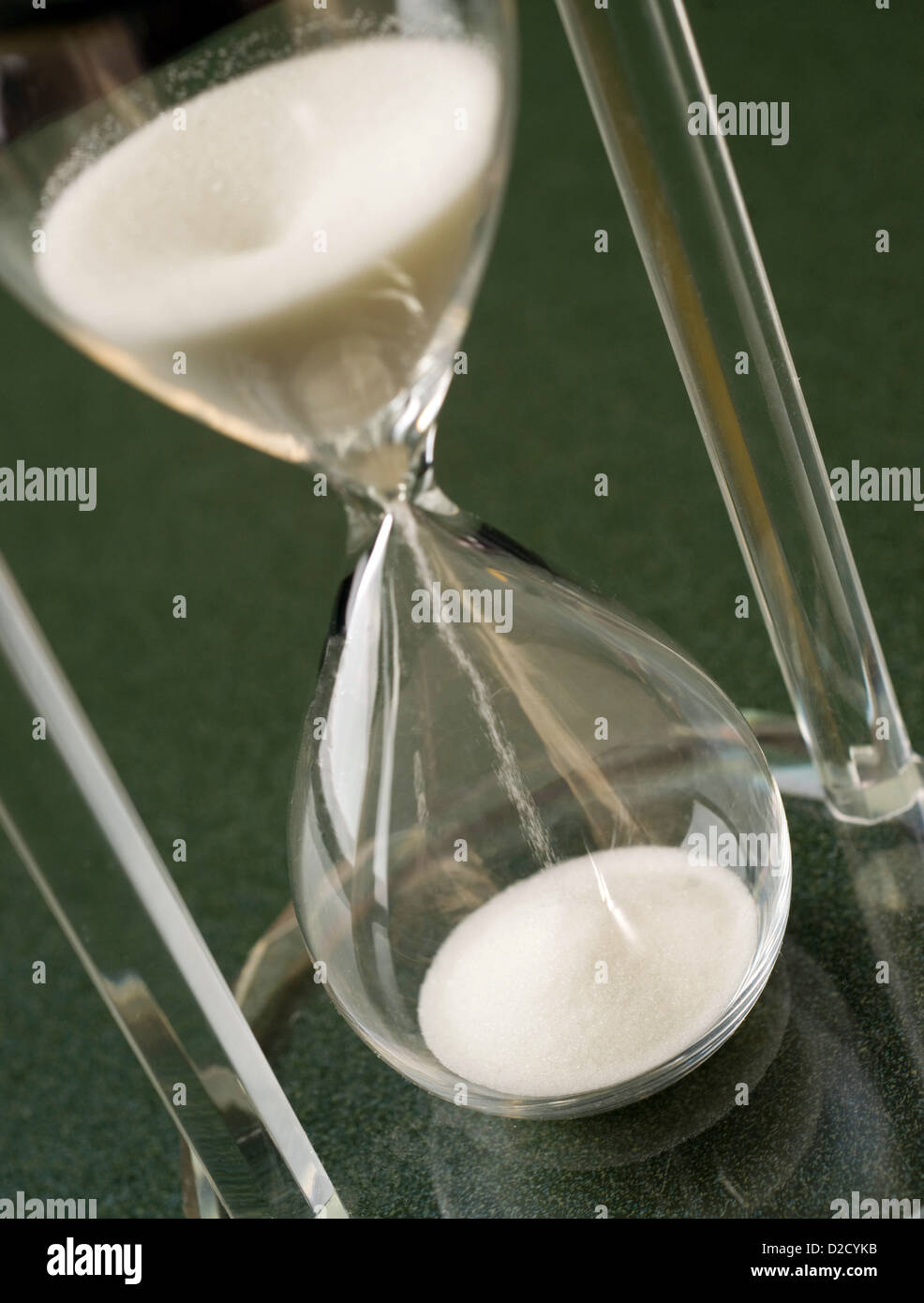 Sand fällt nach unten durch ein Stunde Kristallglas sitzen auf der Tischplatte Stockfoto