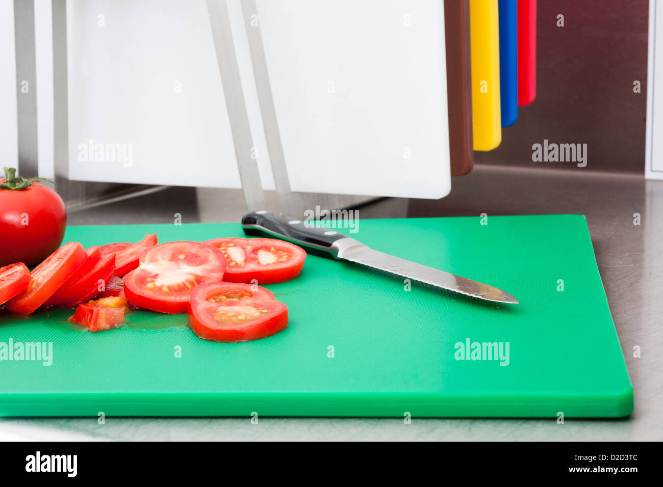 Schneiden Sie Tomaten schneiden Tomaten auf dem entsprechenden farbkodierten Brett Stockfoto
