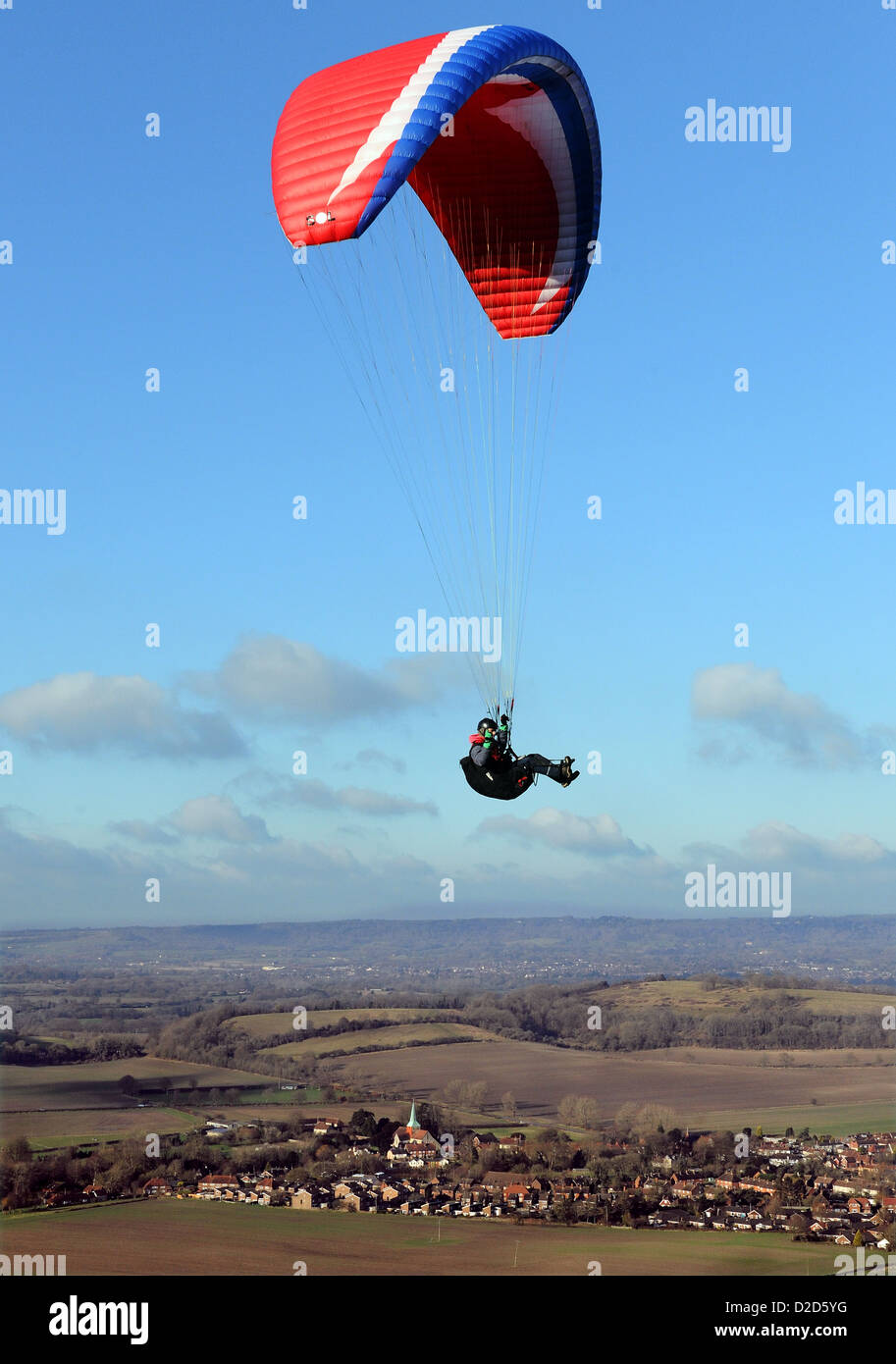 Ein männliche Gleitschirm fliegt über den South Downs in West Sussex mit eine rote Rutsche an einem schönen Tag mit blauem Himmel und weißen Wolken Stockfoto