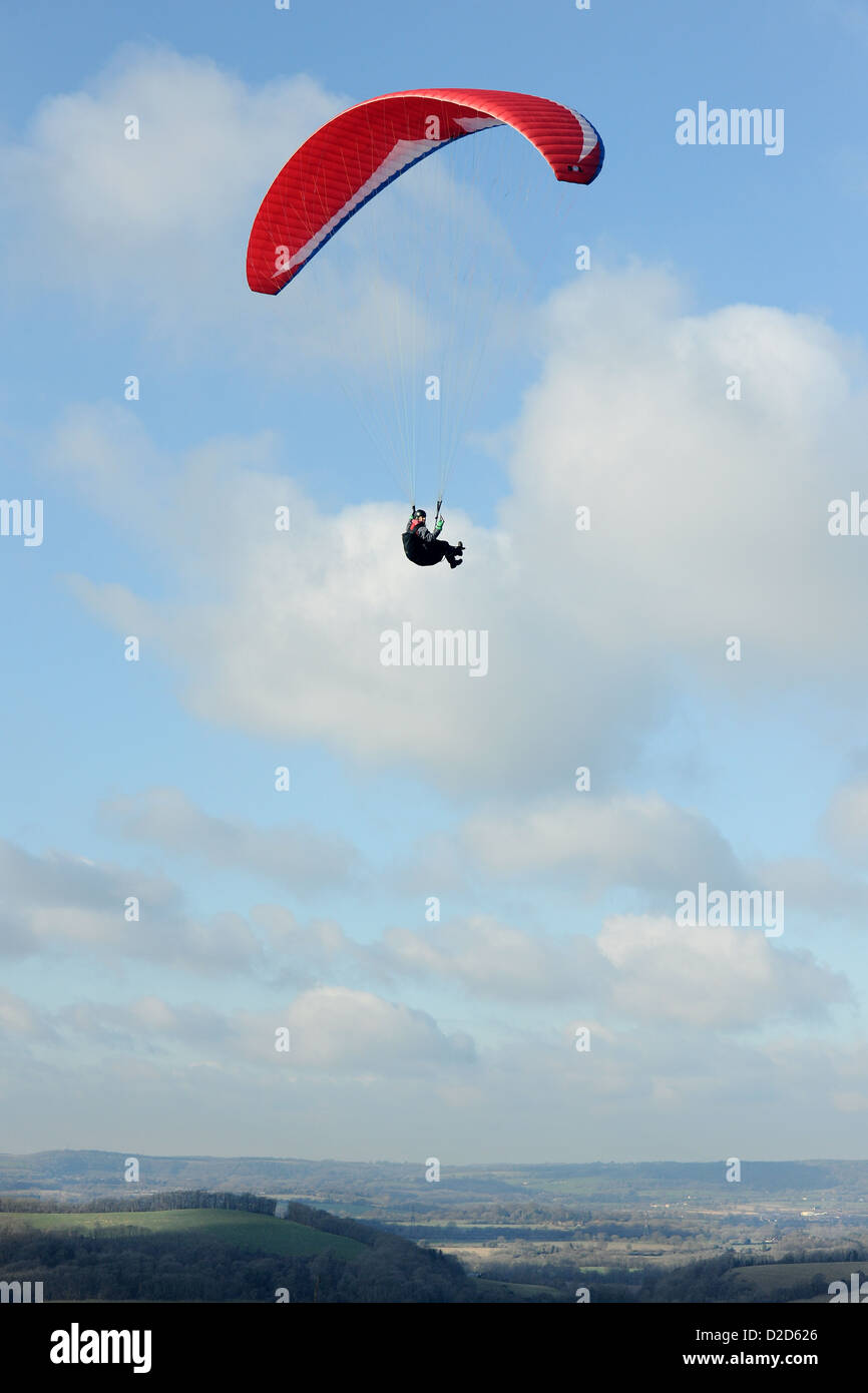 Ein männliche Gleitschirm fliegt über den South Downs in West Sussex mit eine rote Rutsche an einem schönen Tag mit blauem Himmel und weißen Wolken Stockfoto