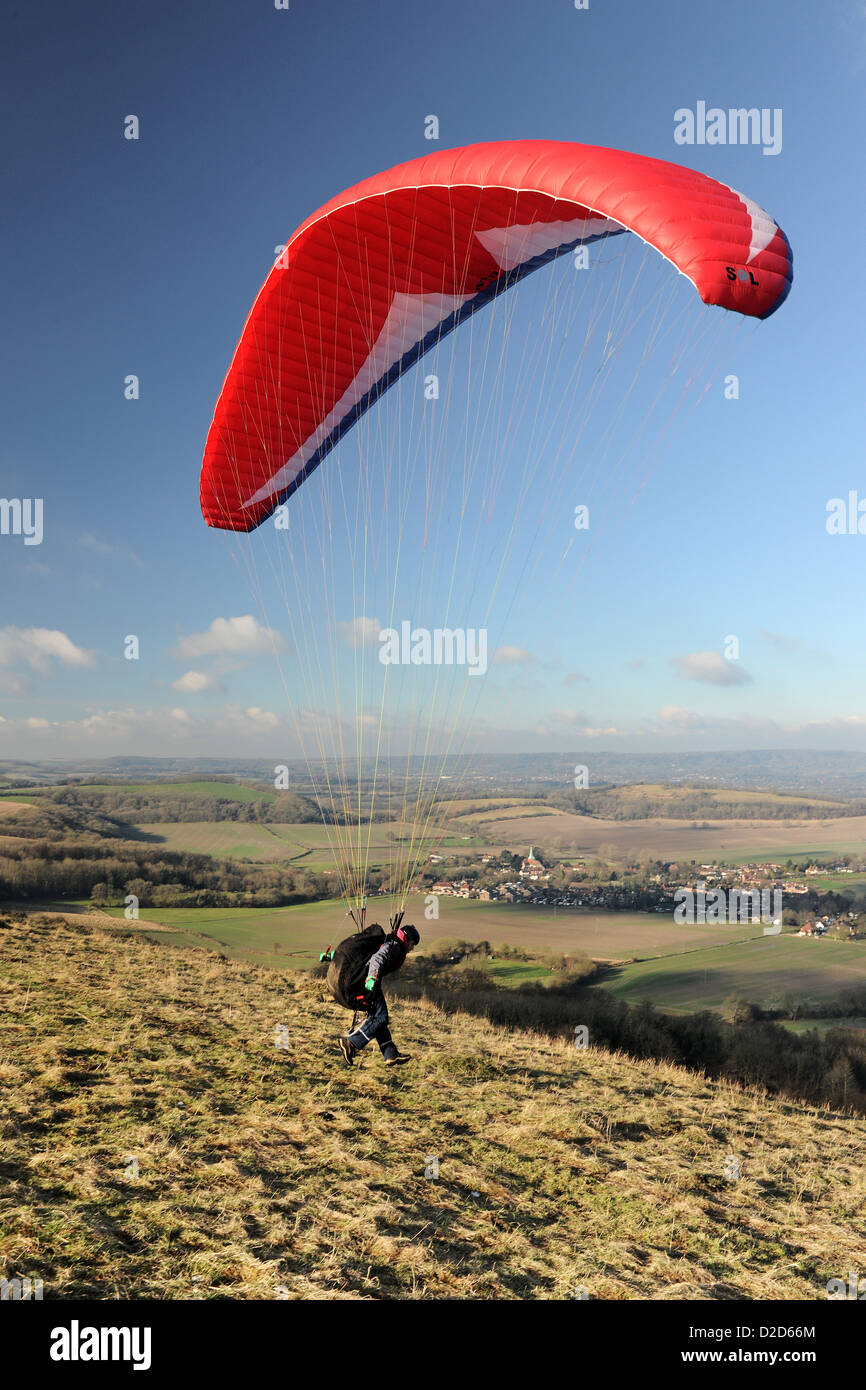 Ein männliche Gleitschirm zieht über den South Downs in West Sussex mit eine rote Rutsche an einem schönen Tag mit blauem Himmel und weißen Wolken Stockfoto