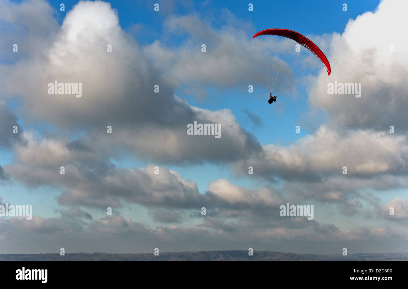 Ein männliche Gleitschirm fliegt über den South Downs in West Sussex mit eine rote Rutsche an einem schönen Tag mit blauem Himmel und weißen Wolken Stockfoto
