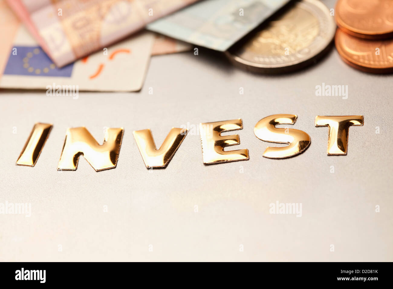Einziges Wort "investieren" neben Euro-Geld Stockfoto