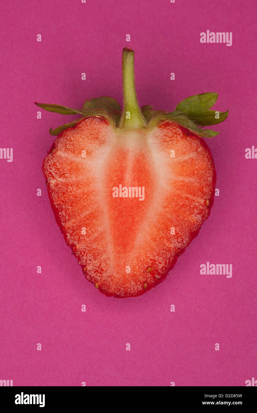 Eine halbierte Erdbeeren auf einem rosa Hintergrund Stockfoto