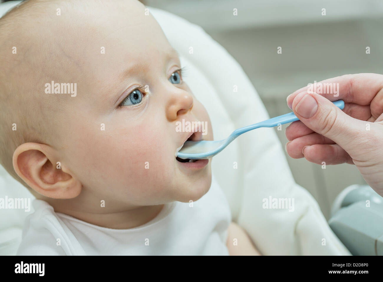 Mutter Löffel füttern ihres Sohnes am Hochstuhl Stockfoto