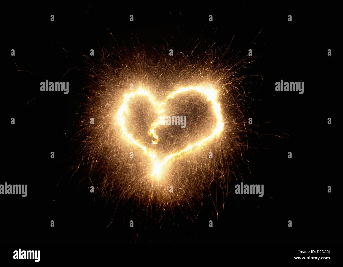 Die Form eines Herzens mit einer Wunderkerze vor einem schwarzen Hintergrund gezeichnet Stockfoto