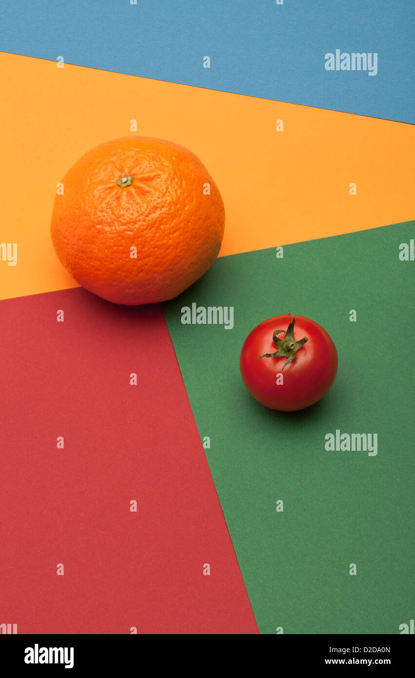 Eine Orange und eine Tomate platziert auf einem Multi-farbigen geometrischen Muster Stockfoto