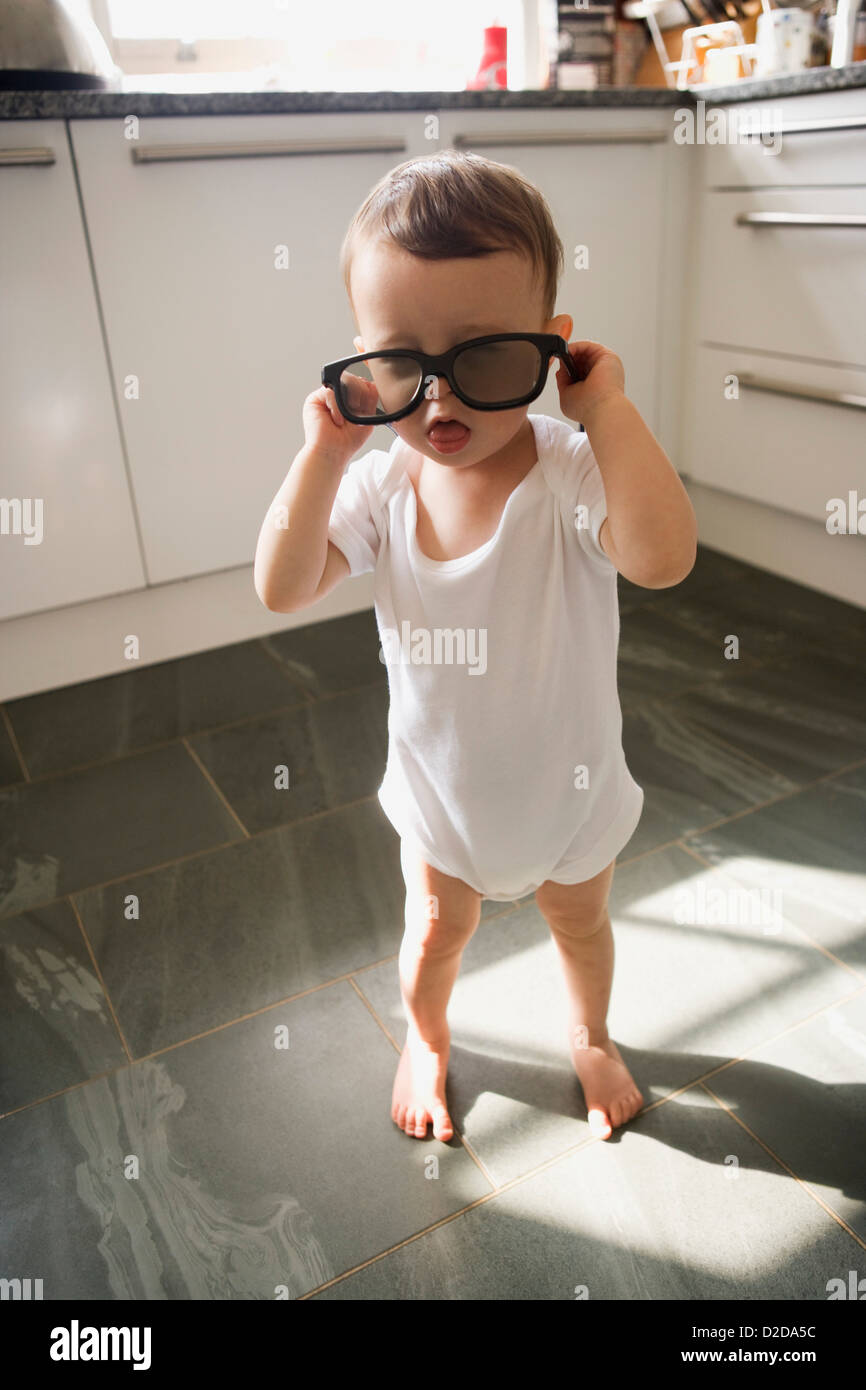 Ein Junge steht in der heimischen Küche spielen mit Sonnenbrille Stockfoto