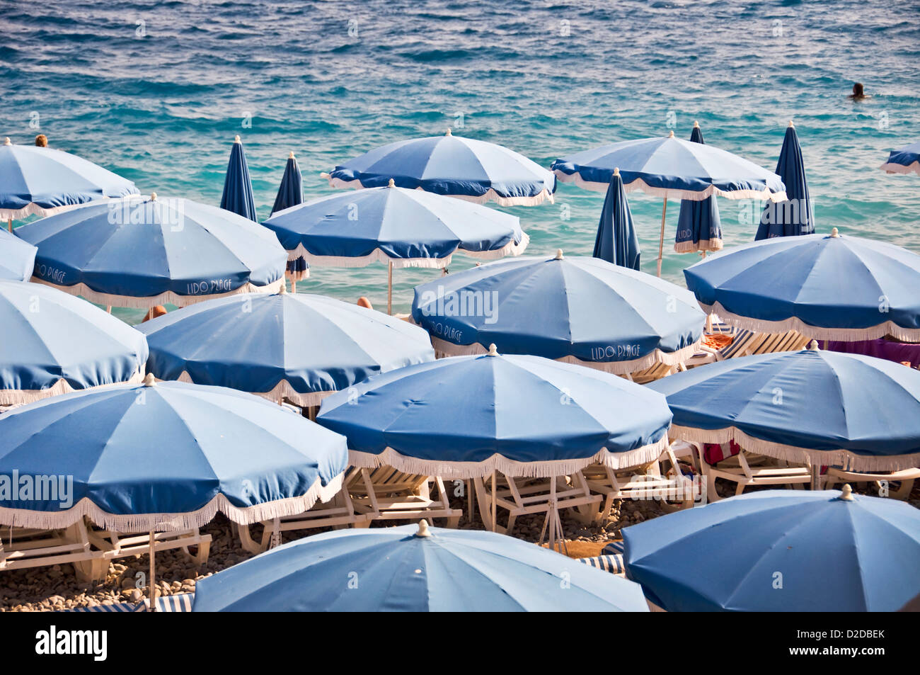 Privatstrand mit blauen Sonnenschirmen, Meer im Hintergrund Ansicht von oben - Nizza, Frankreich Stockfoto