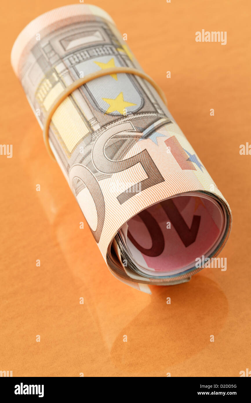 50 Euro Hinweis auf eine Rolle des Euro mit einem elastischen Band rollte auf einer Ebene orange Gold Hintergrund. Europa EU Stockfoto