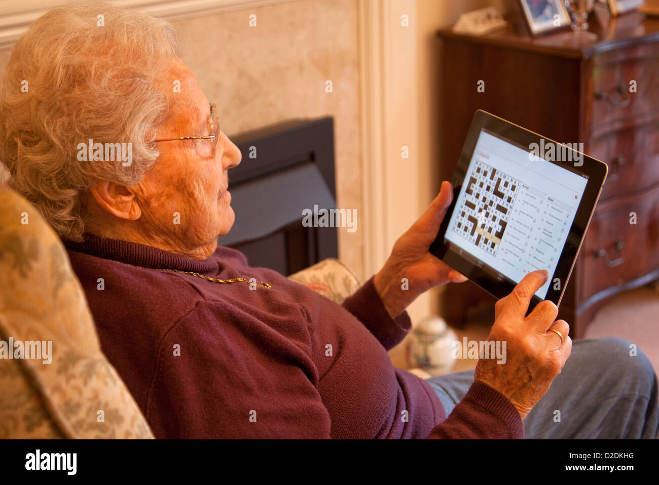 Ältere Frau Rentner mit Brille auf Apple Ipad Tablet zu Hause entspannen und tun Kreuzworträtsel Online Zeitung Stockfoto