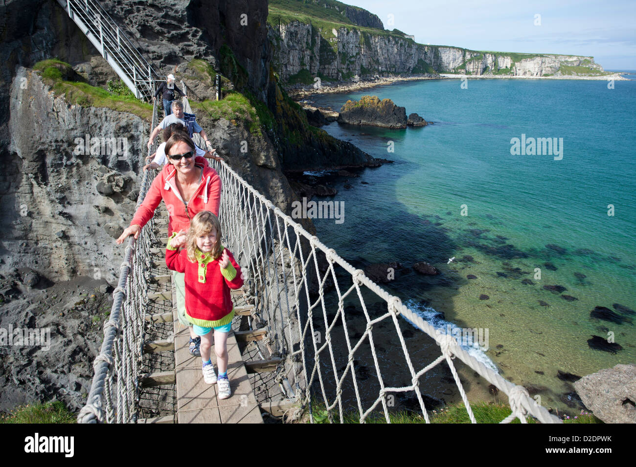 Frau und Kind überqueren Carrick-a-Rede Rope Bridge, County Antrim, Nordirland. Stockfoto