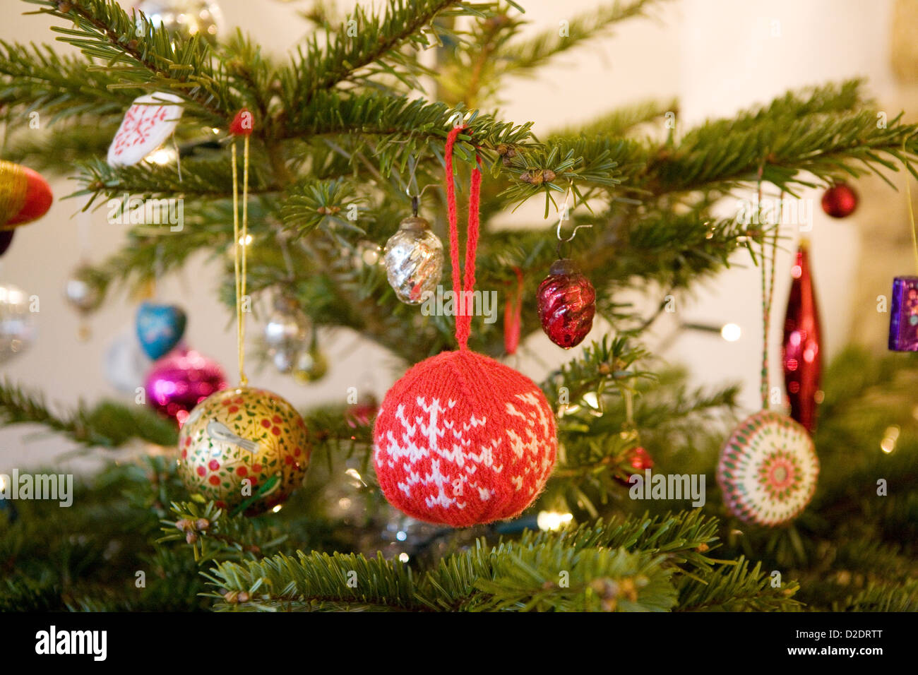 Weihnachtsschmuck an einen echten Nordmann-Tanne (Abies Nordmanniana) Weihnachtsbaum hängen. Strick- und Glas-Kugeln. Stockfoto