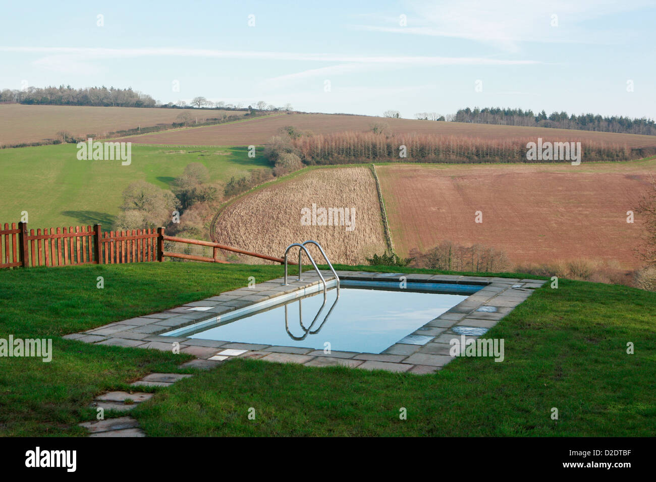 Außenpool mit Blick auf eine schöne Aussicht in Ashcombe, Devon, England. Sonnenschein und blauen Himmel spiegelt sich im Wasser. Stockfoto