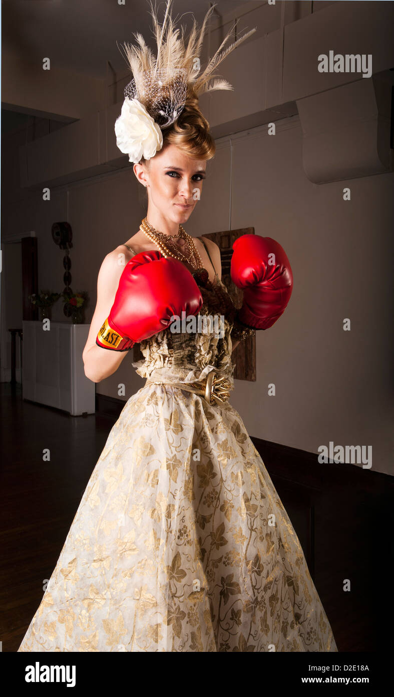Ein weibliches Modell in ihren Zwanzigern mit Boxhandschuhen trägt ein Kleid von Stella Anleihen entworfen, gemacht von Papier Stockfoto