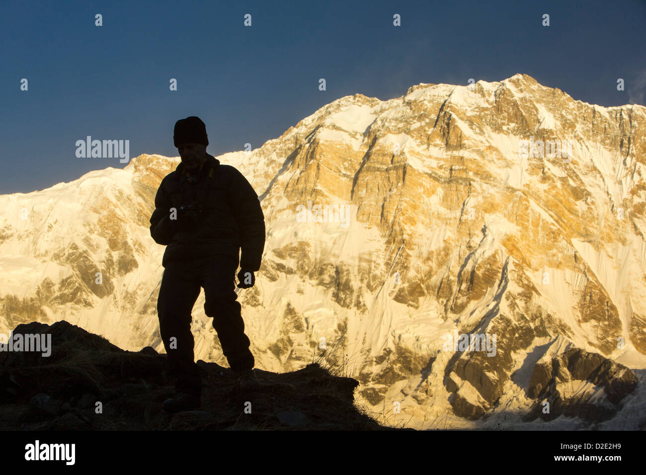 Ein Trekker mit Alpenglühen bei Sonnenaufgang am Annapurna South und Annapurna Fang, Nepelese Himalaya. Stockfoto