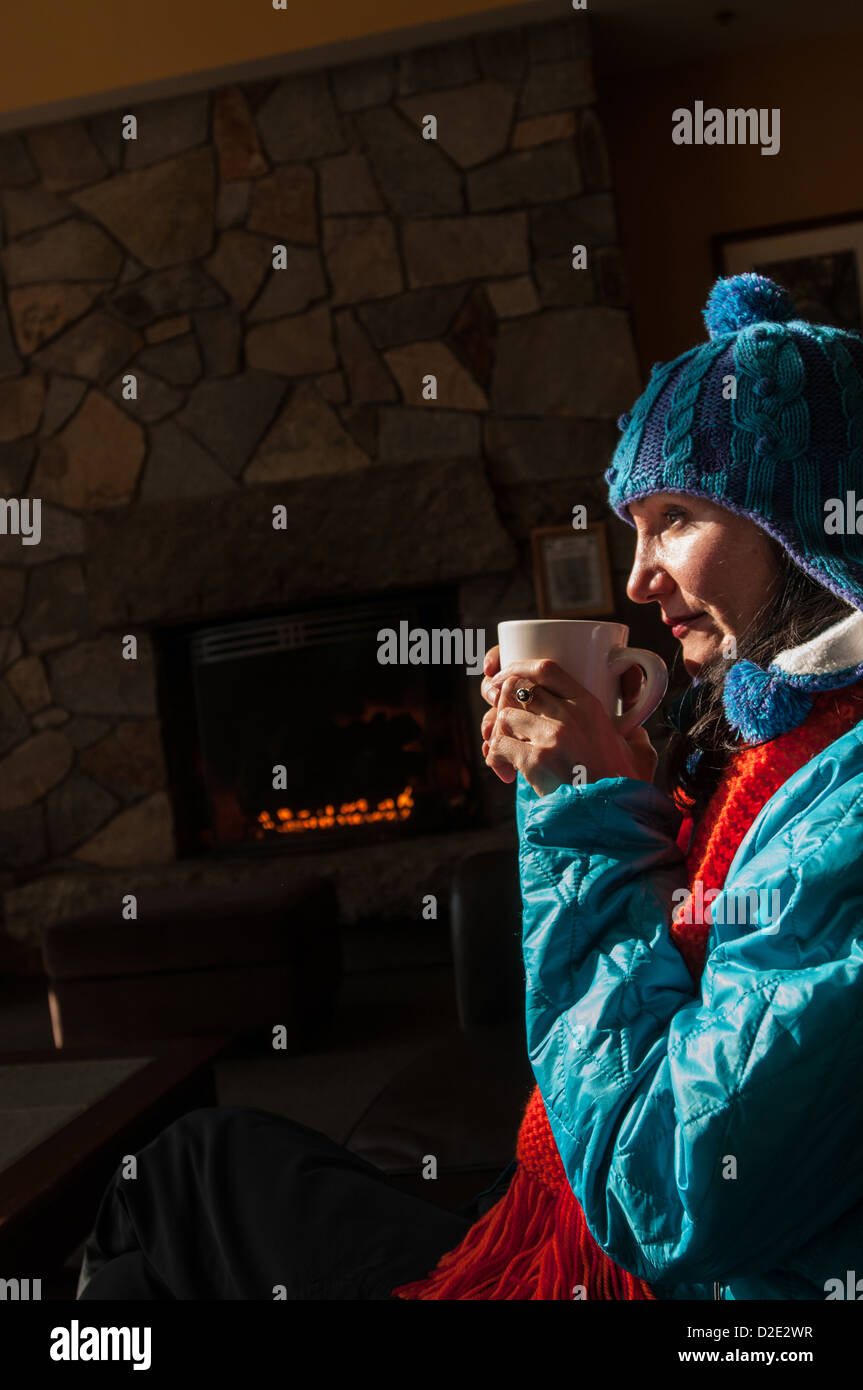 Frau, genießen eine Tasse heiße Schokolade in der Nähe einer Feuerstelle in der Lodge in Crawford Notch, NH. Stockfoto