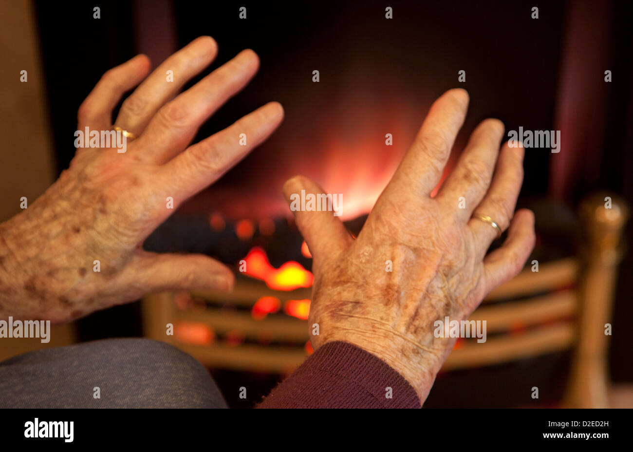 Alten Womans kalte Hände Erwärmung auf ein Feuer Stockfoto