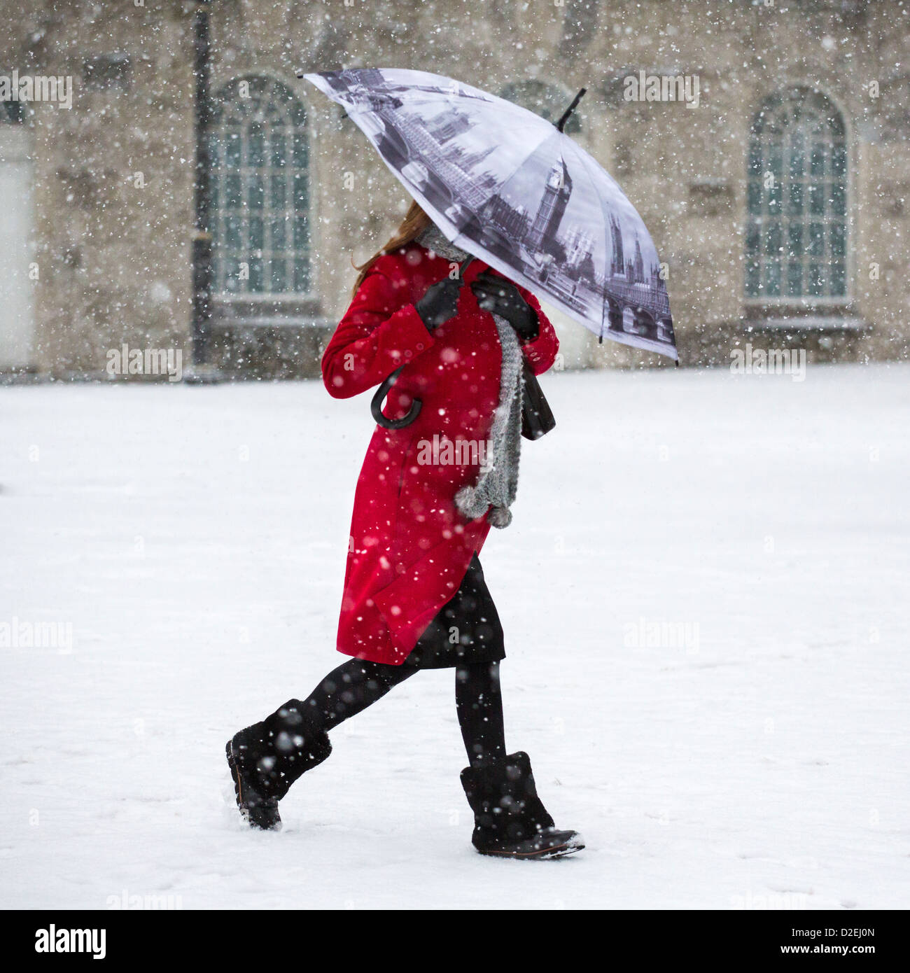 Eine Frau zu Fuß durch den Schnee in Victoria Square, Birmingham, UK. Der Schirm zeigt den Houses of Parliament in London. Stockfoto