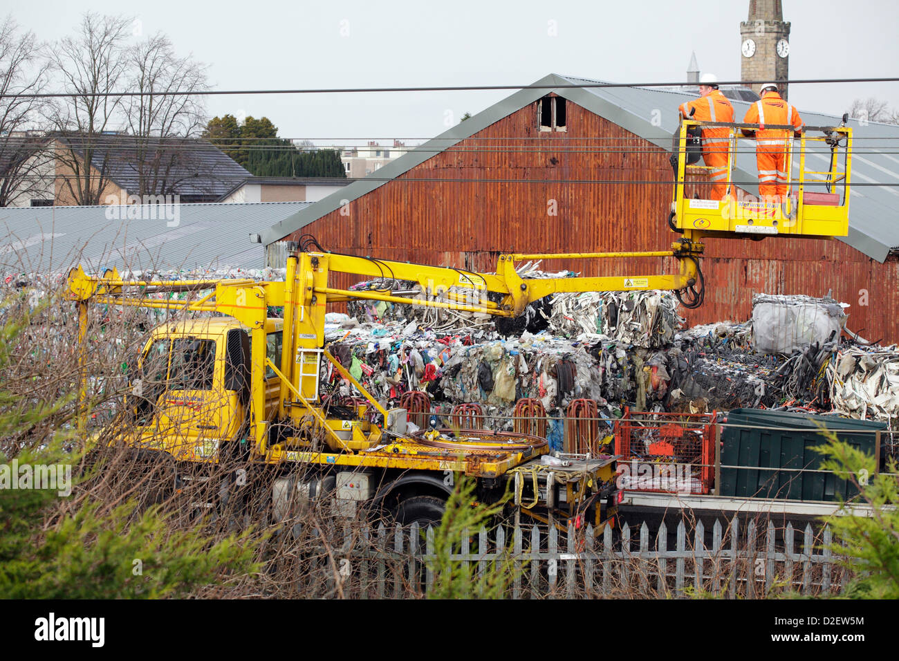 Johnstone, Renfrewshire, Schottland, Großbritannien, Dienstag, Januar 2013. Network Rail Engineers untersuchen die Oberleitungskabel nach einem Brand in der WRC-Recyclingfabrik auf Schäden, die im Hintergrund zu sehen sind und zu Annullierungen, Verzögerungen und Überarbeitungen der Zugdienste auf der Strecke zwischen dem Hauptbahnhof Glasgow und Ayr führen Stockfoto