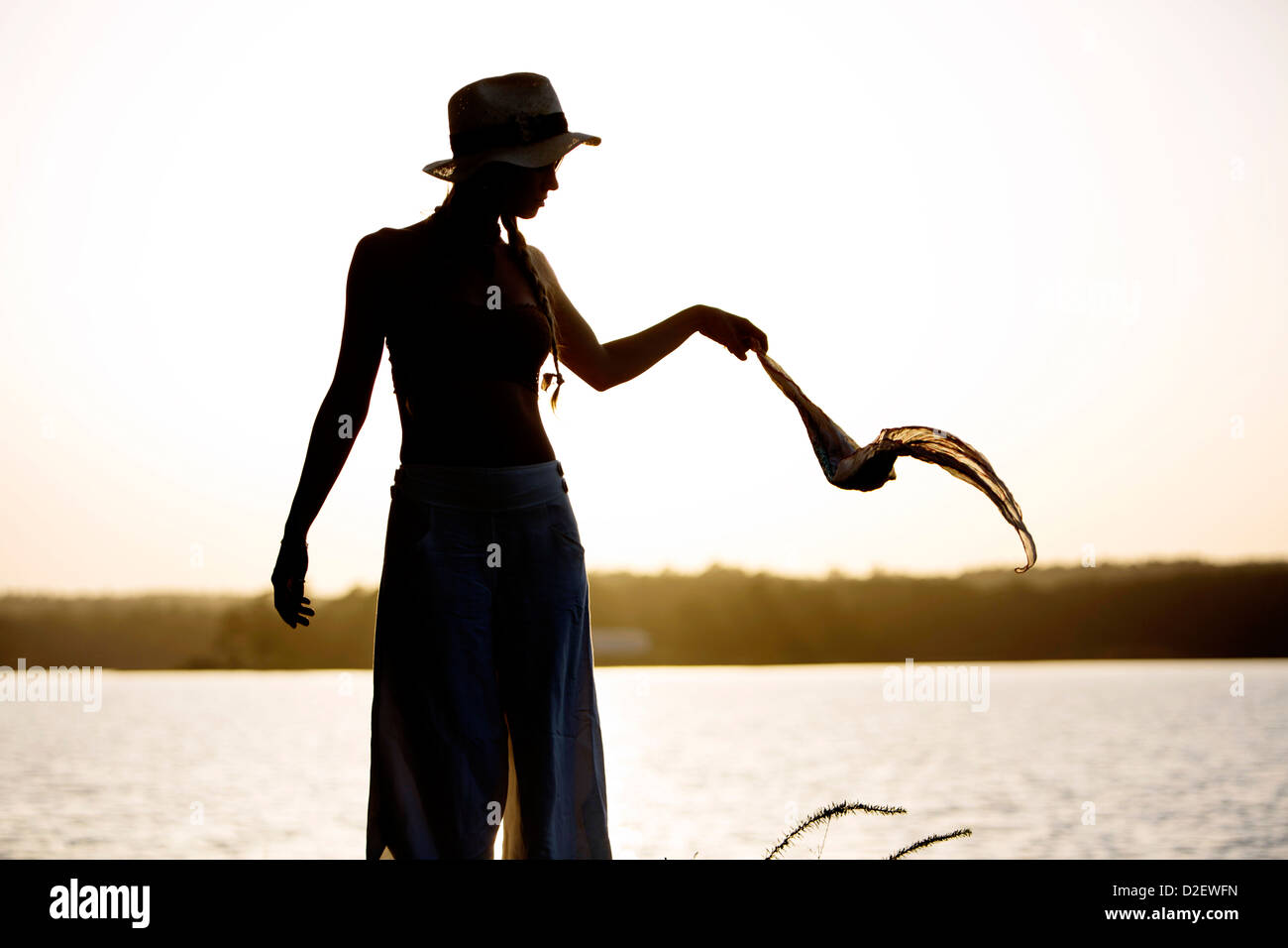 Eine junge Frau hält einen Schal im Wind am Ufer des Lake Martin, Alabama. Stockfoto