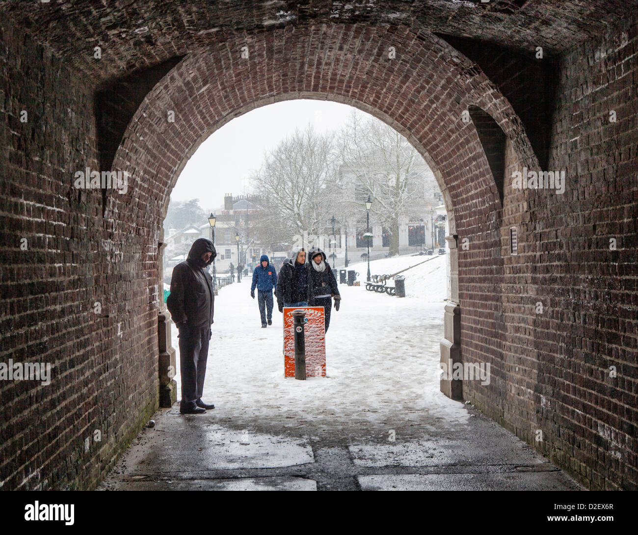 Ältere Menschen Schutz vor den fallenden Schnee unter Richmond Brücke im Winter, Richmond upon Thames, London, Surrey, Großbritannien Stockfoto