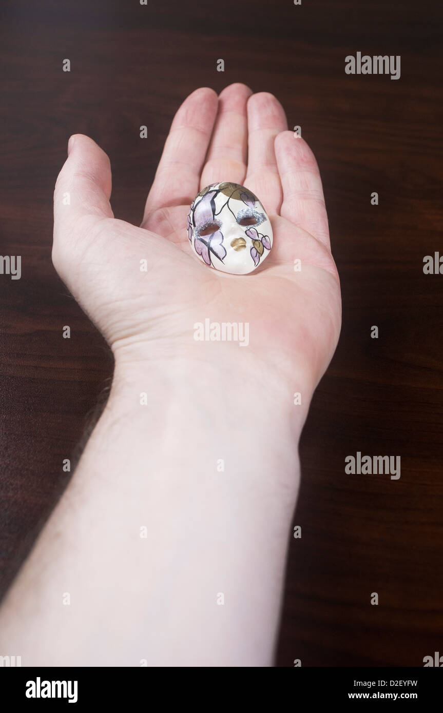 Hand hält eine kleine Maske Stockfoto
