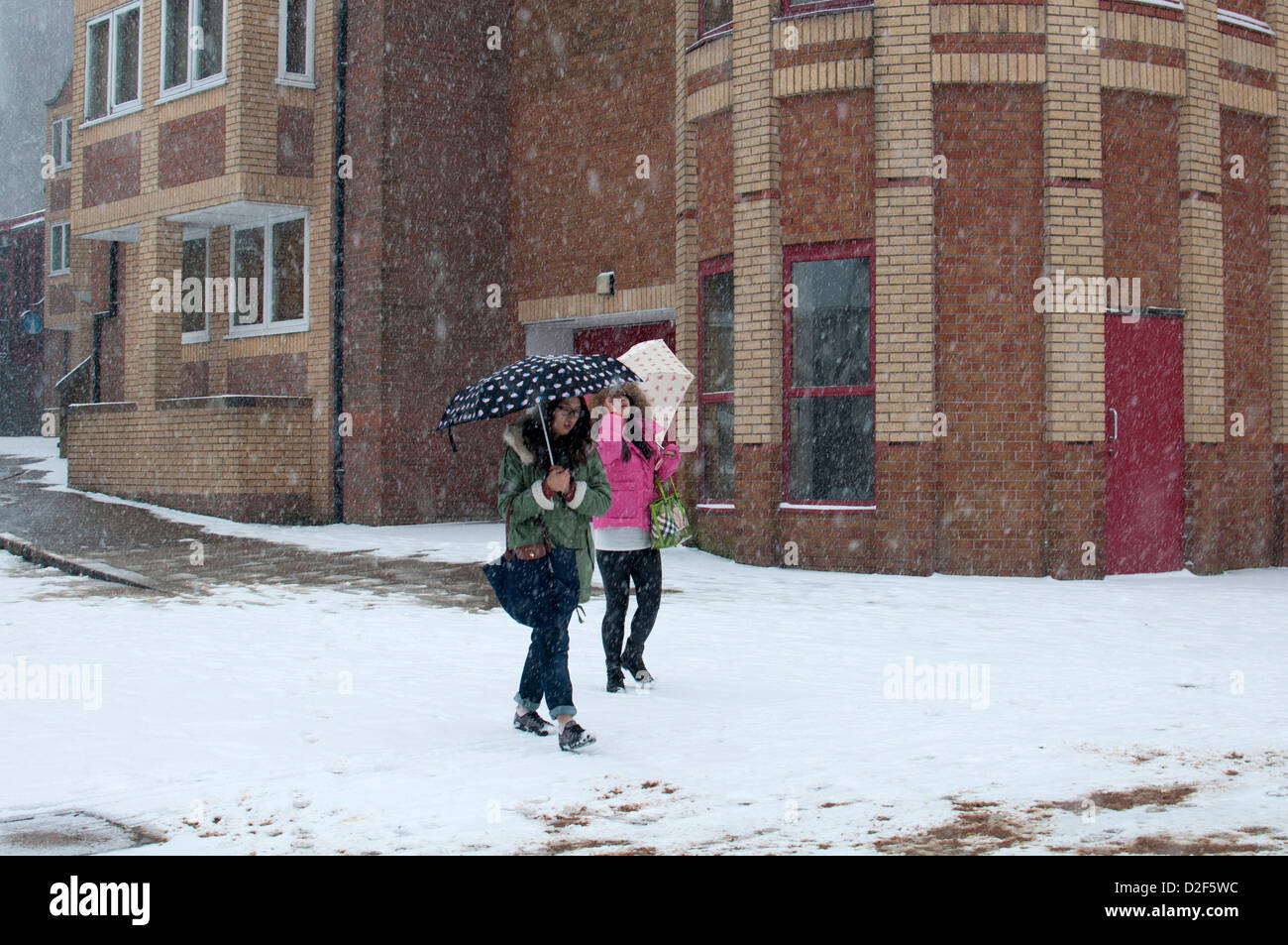 Junge Frauen mit Sonnenschirmen in Schneewetter, Stadtzentrum von Coventry, UK Stockfoto