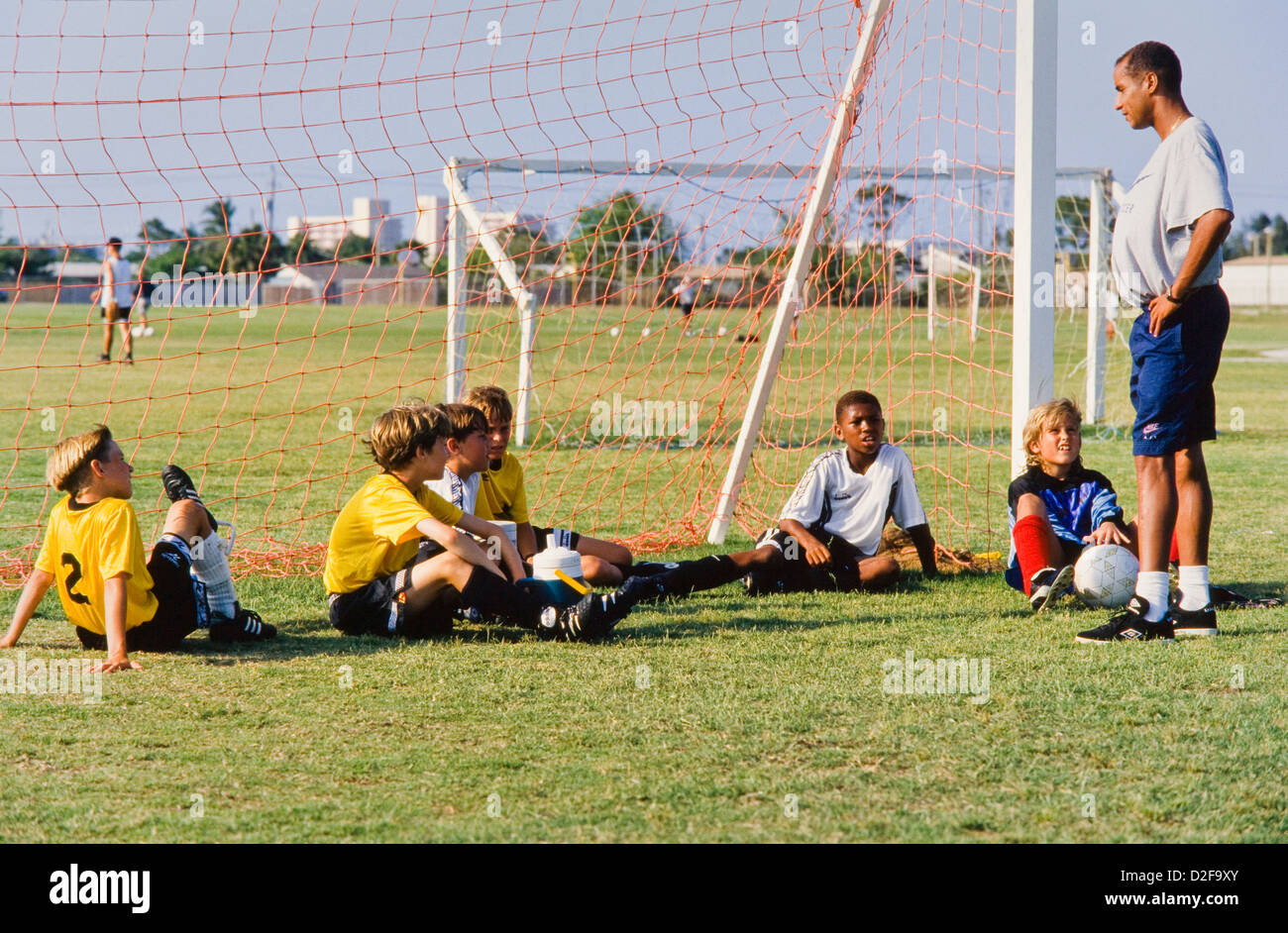 Kids Fußball-Team, Mädchen und Jungen gemeinsam mit Trainer unterrichten Fähigkeiten, Teamarbeit, Teamgeist, Melbourne, Florida Stockfoto