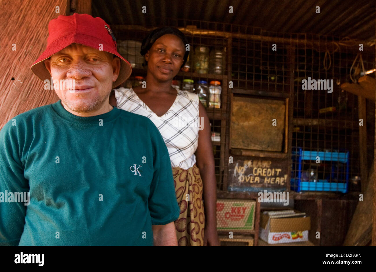 Porträt eines afrikanischen Albino-Mannes und seiner Frau vor ihrem Geschäft. Stockfoto