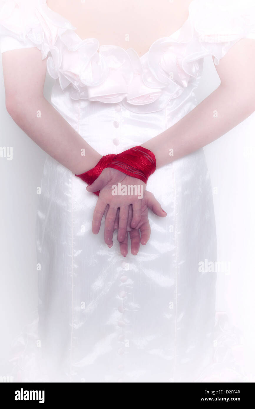 eine Frau in einem weißen Kleid mit gefesselten Händen Stockfoto