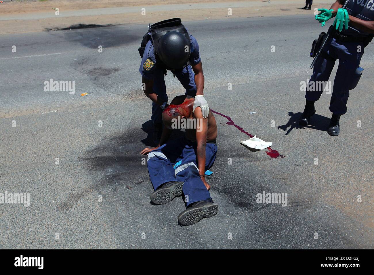 SASOLBURG, Südafrika: Polizeibeamte neigen dazu, eine verwundete Demonstranten am 22. Januar 2013, in Sasolburg, Südafrika. Die Ankündigung der Regierung, Kommunen im Freistaat zu verschmelzen löste Empörung in Zamdela Township-Bewohner. (Foto von Gallo Images / Zeit / Alon Skuy) Stockfoto