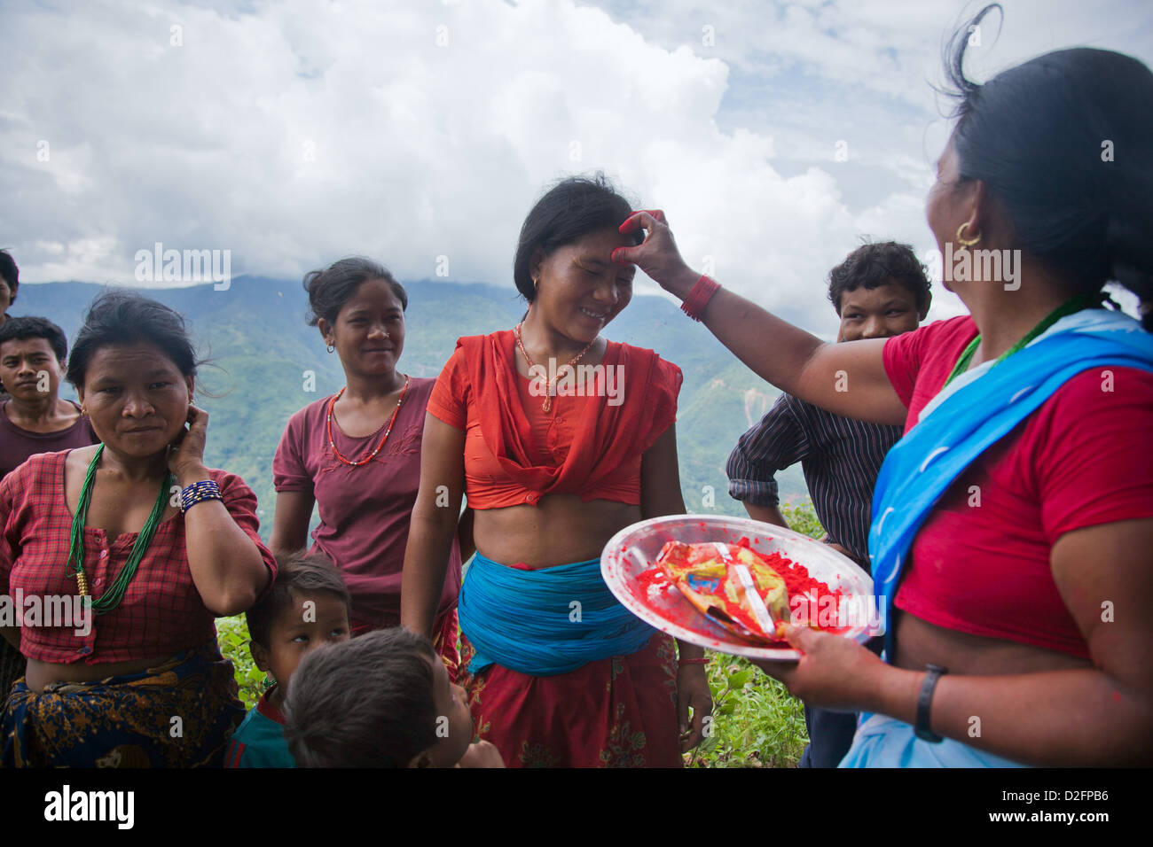 Sanamaya Chepang gibt Tika, Menschen in einem örtlichen sammeln, eine Hindu-Tradition bedeutet viel Glück und Gesundheit. Stockfoto
