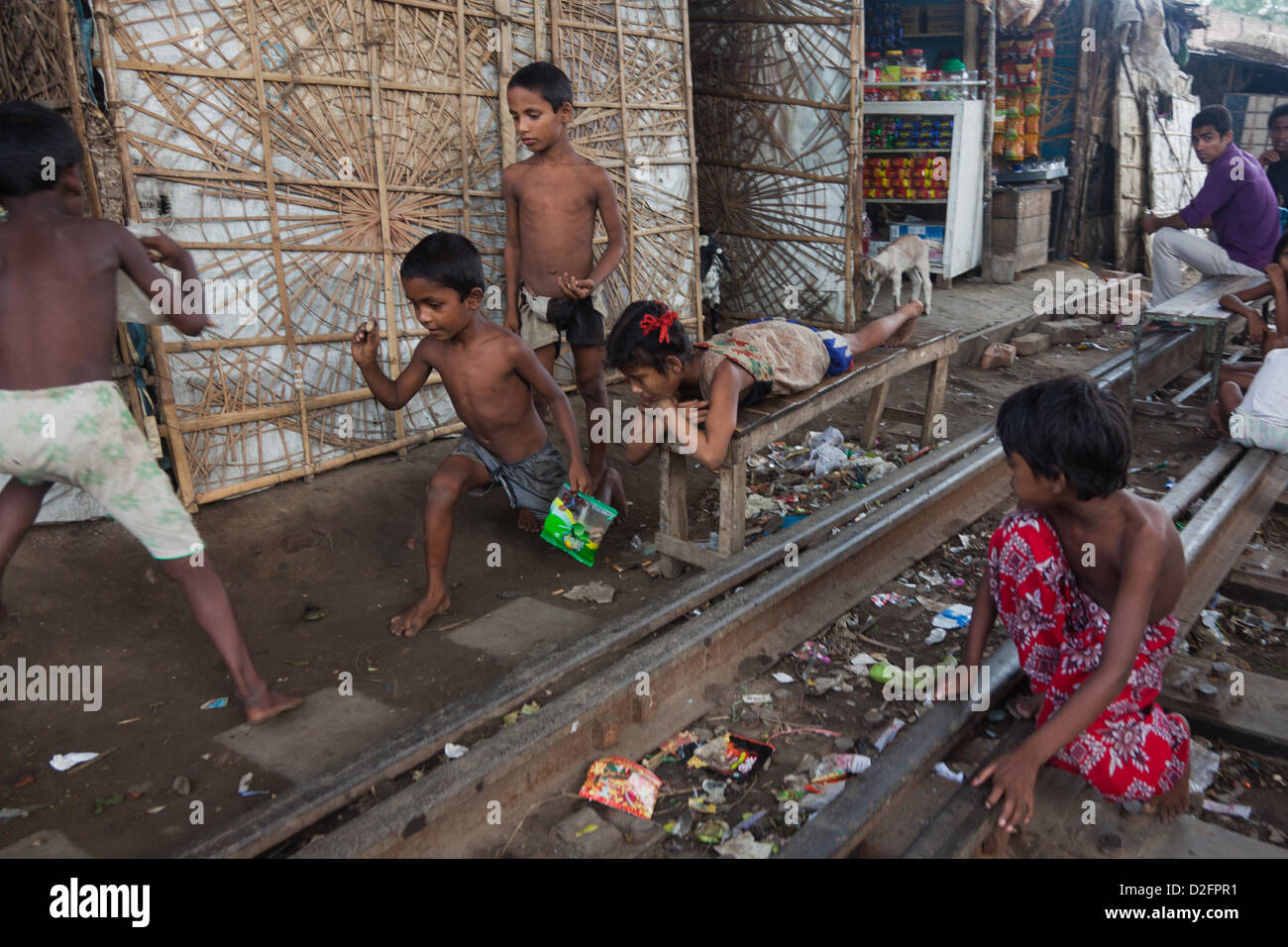 Kinder spielen auf den Bahngleisen, ihre Häuser befinden sich direkt neben den Beschäftigten Spuren führen in und aus Dhaka. Stockfoto