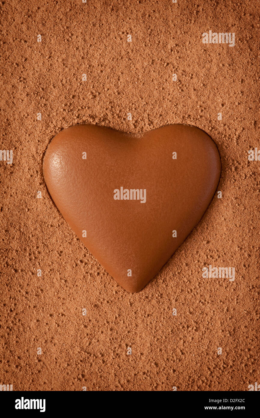 Vollmilch Schokolade Herz auf einem strukturierten Hintergrund von Coco Pulver gemacht Stockfoto