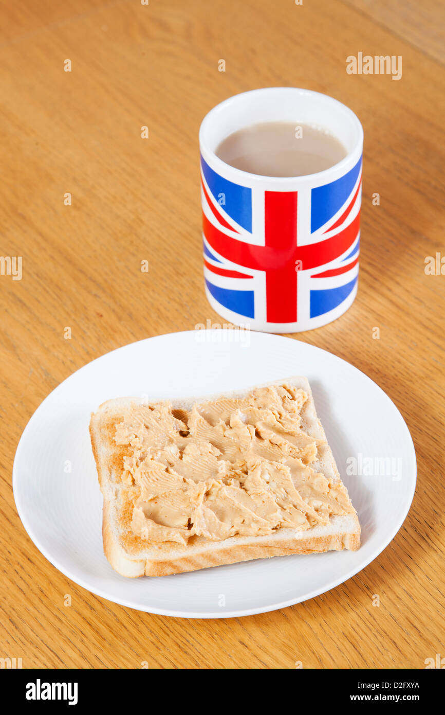 Britische Kaffeetasse und Scheibe Brot mit Butter auf Tisch Stockfoto