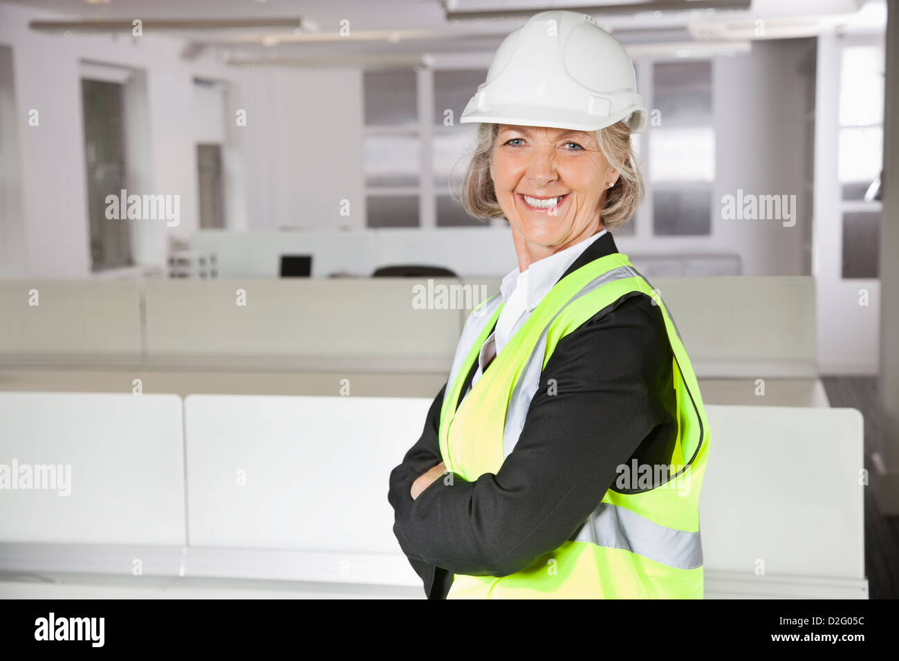 Porträt von lächelnden senior Frau im Reflektor Weste und Schutzhelm im Büro Stockfoto