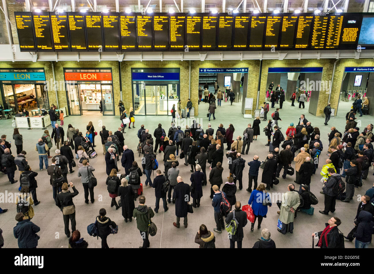 Die Leute am Bahnhof Kings Cross, London, UK - mit Blick auf die Abfahrt Platten im abendlichen Hauptverkehrszeit mit gestrichenen Züge verzögert Stockfoto