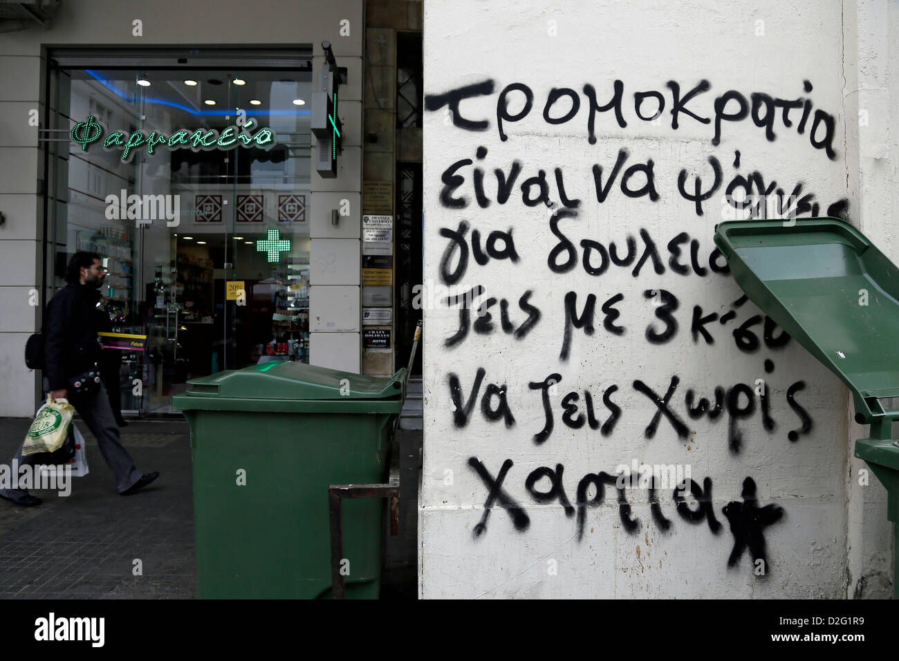 Thessaloniki, Griechenland. 22. Januar 2013. Ein Mann geht vorbei ein Graffiti, das auf Griechisch lautet: '' Terrorismus = Job Suche '' im nördlichen Griechenland Stadt von Thessaloniki. Anstieg der registrierten Arbeitslosen um 1,44 % im Vergleich zum Vormonat und 9.16 % ab Dezember 2011, zeigen Statistiken des griechischen Arbeitskräften Beschäftigung Organisation (OAED) für Dezember 2012. Registrierte Arbeitslosen in OAED Register belief sich im Dezember bei 797.578 Menschen. Griechenland hat im sechsten Jahr der wirtschaftlichen Rezession und Gesichter zeichnen hohe Arbeitslosigkeit und Obdachlosigkeit. Stockfoto