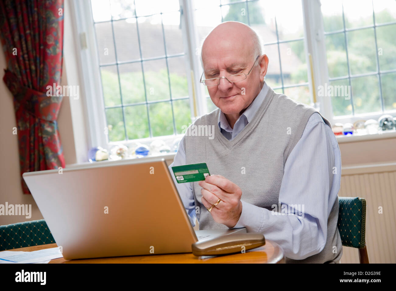 Ältere Mann mit Laptop, um Rechnungen zu bezahlen / online-shopping mit Kreditkarte Stockfoto