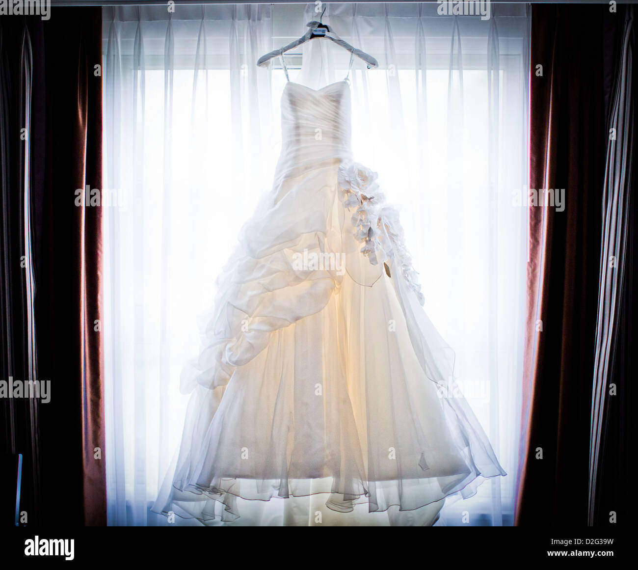 Foto von einem schönen weißen Brautkleid in einem Fenster aufhängen Stockfoto