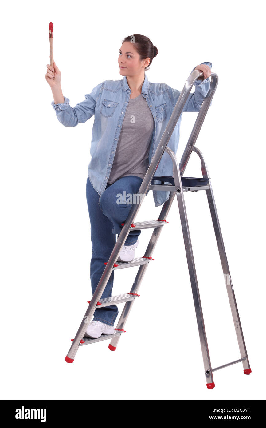 junge Malerin auf Leiter mit erhöhten Pinsel Stockfoto