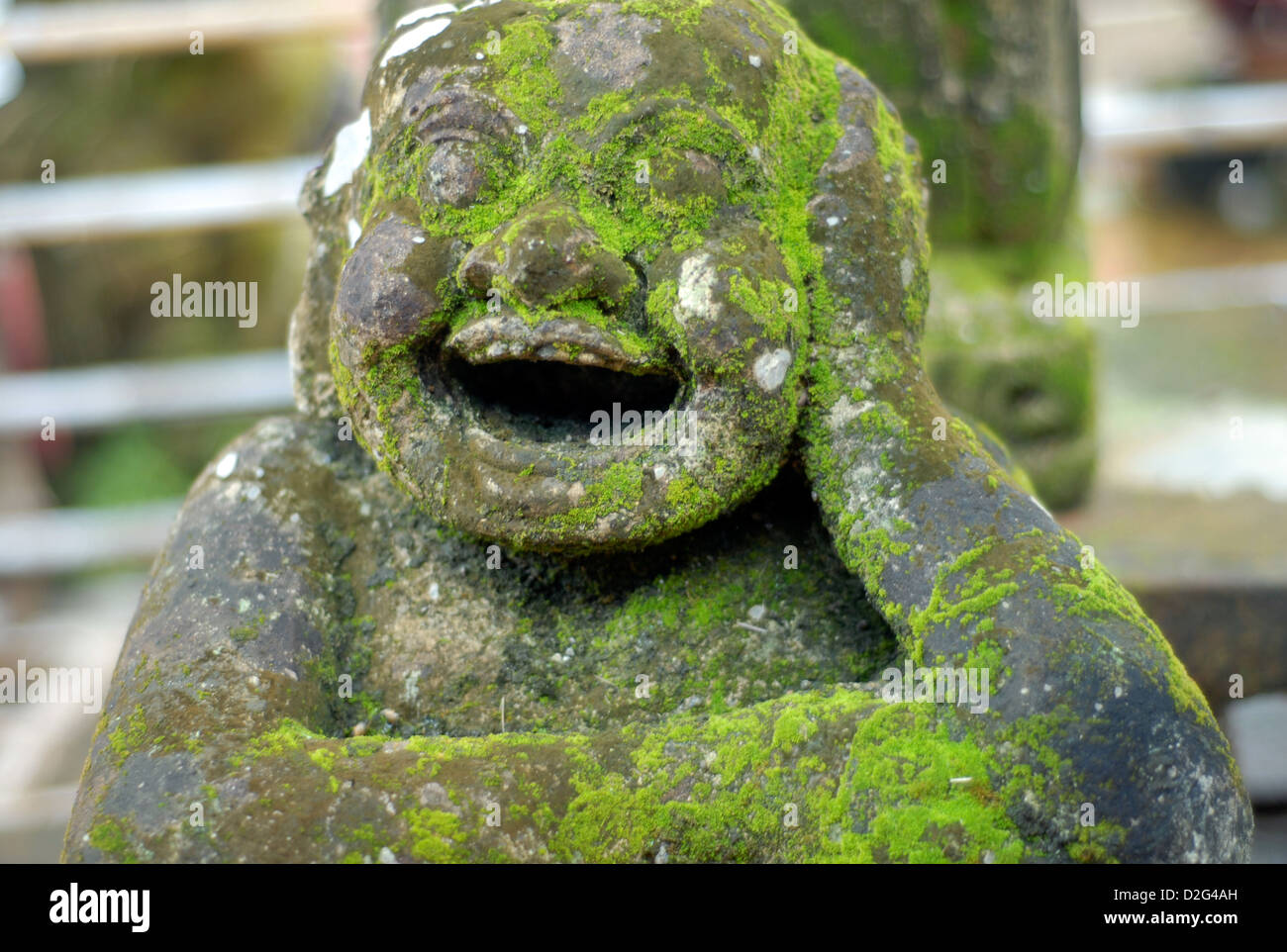 Moos bedeckt geschnitzt Steinstatue ein dicker Mann auf dem Steg in Ban Bang Bao Koh Chang Thailand lachen Stockfoto