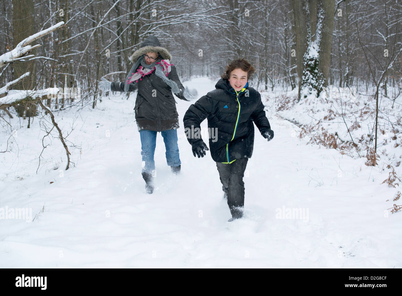 Mutter und Sohn im Schnee jagen im Wald. Glücklich laufen Stockfoto