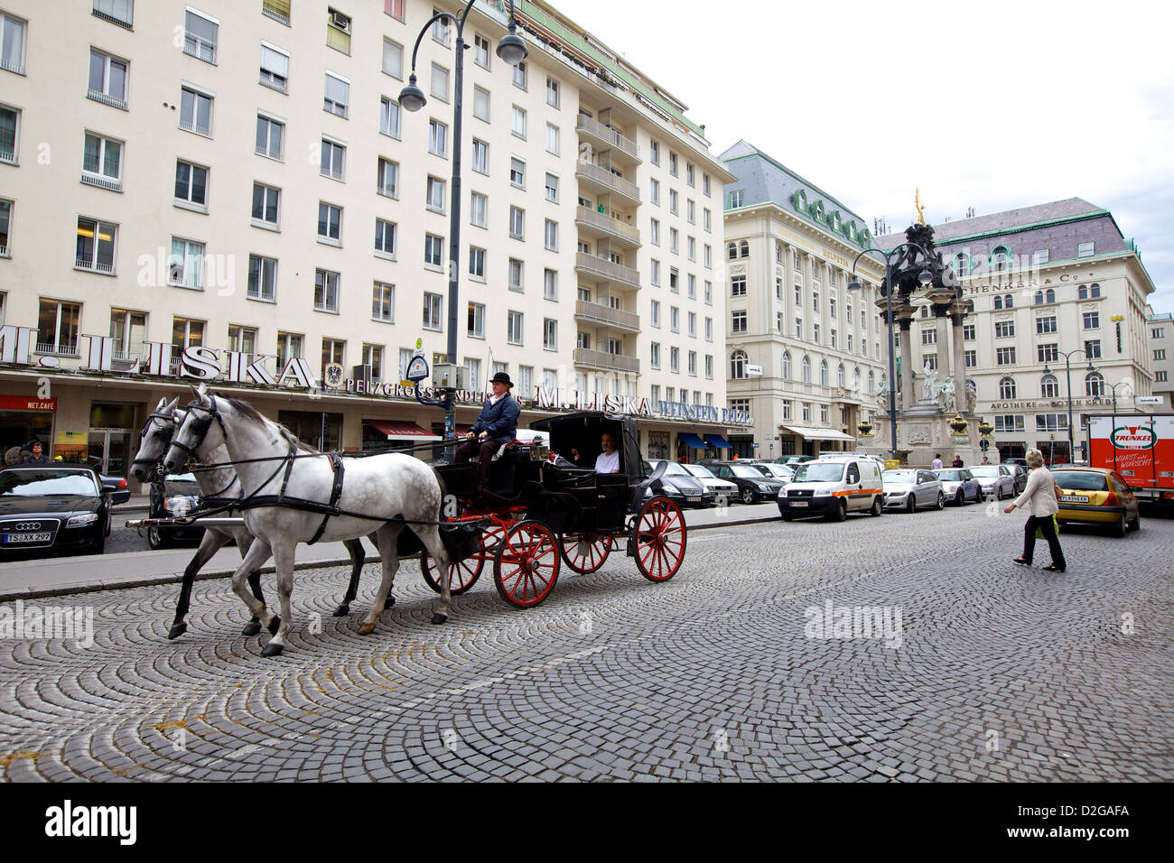 Eine Pferdekutsche fährt durch eine Kopfsteinpflasterstraße in Wien, Österreich, und bietet einen Einblick in die traditionellen Verkehrsmittel im modernen Stadtleben Stockfoto