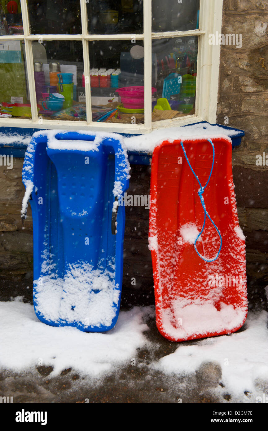 Schlitten im Schnee vor Hardware-Geschäft bei Hay-on-Wye Powys Wales UK bedeckt Stockfoto