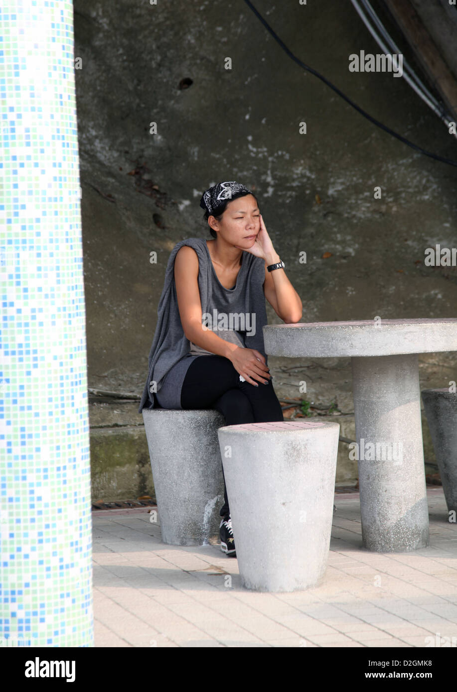 Es ist ein Foto einer chinesischen Frau, die an einem Tisch sitzt. Sie schlafen oder ruhen, haben ein Nickerchen oder denken, träumen warten Stockfoto
